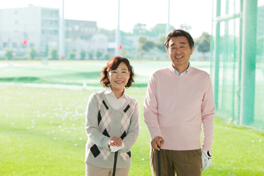 ゴルフ場に立つ熟年夫婦 - Powered by Adobe