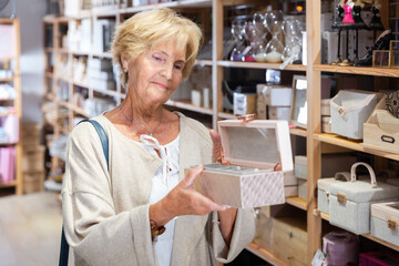 Smiling woman consumer choosing wooden jewelry box in furniture shop