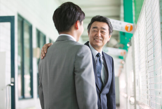 バッティングセンターで話すビジネスマン2人