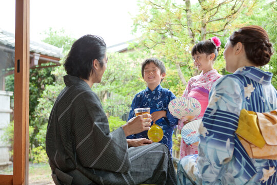 縁側で話す浴衣姿の日本人家族