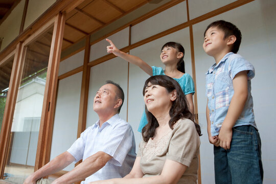 縁側に座る祖父母と孫