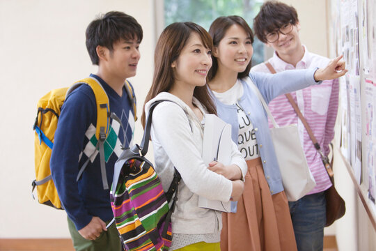 掲示板を見て話す学生たち
