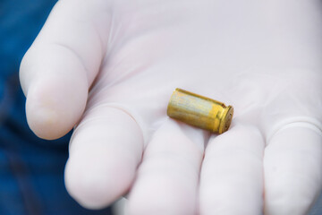 Blur pistol bullet shells holding in white gloved fingers 
