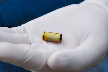 Blur pistol bullet shells holding in white gloved fingers 