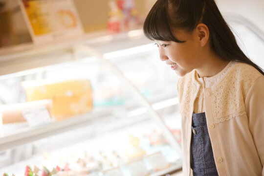 ケーキのショーケースを見る女の子