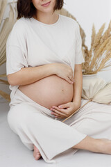 Smiling pregnant woman in boho style. A young pregnant girl in eco-style, on a white empty...