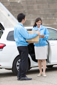 車から荷物を運ぶビジネス男女