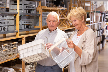 Fototapeta na wymiar Positive couple elderly customers buying storage baskets in a household goods store
