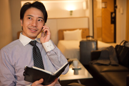 ホテルの部屋で電話をする男性