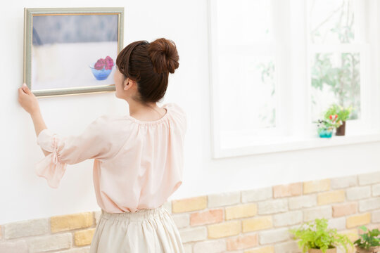 フレームを壁にかける女性