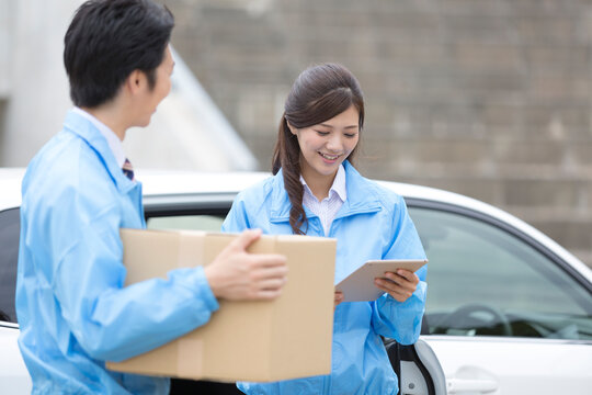 車から荷物を運ぶビジネス男女