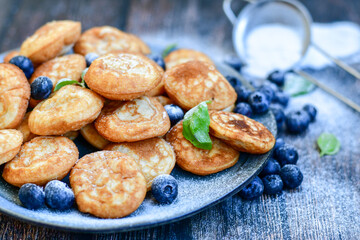 Homemade Dutch Poffertjes  Mini Pancakes with butter , Powdered Sugar  and blueberries