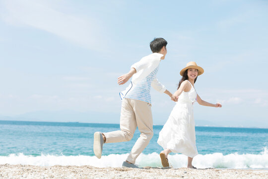 海辺で手をつないでいるカップル