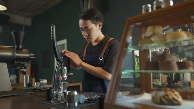 Asian man barista making hot espresso shot from flair espresso coffee maker at cafe. Male coffee shop owner brewing black coffee serving to customer. Small business restaurant food and drink concept