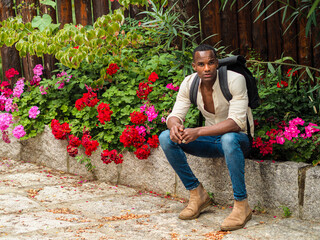 african young fit man nomad traveler resting near fllowers in a park