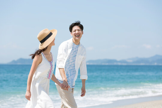 海辺で手をつないでいるカップル