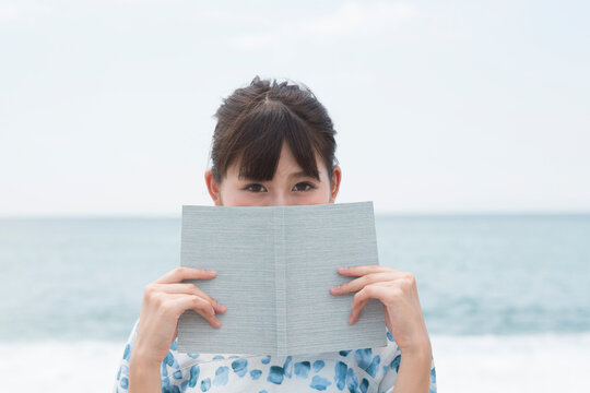 海辺で本を持っている女性