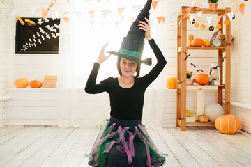 Young beautiful woman in witch costume ready for Halloween celebration in Halloween room decoration