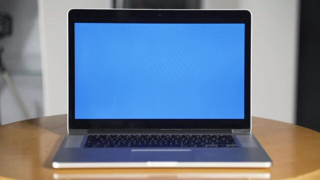 New laptop with editable blue screen on a round wooden office table.