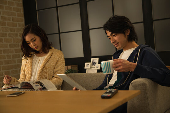 タブレットＰＣと雑誌を見るカップル - Powered by Adobe