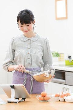 タブレットPCを見ながら調理する女性