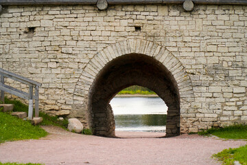 Fototapeta na wymiar Arch in a stone wall. Passage to the river.