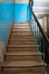 Old abandoned concrete staircase with beautiful railings in an empty building with blue walls