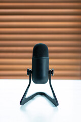 Black microphone on white table and blurry background.