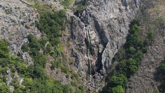 Lichen covered massive cliff wall with stream fresh waterfall, Cascata da Frecha da Mizarela, Arouca, Portugal