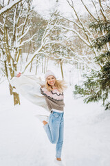 Happy woman in a pink coat and hat running on a winter trail in the park. Leisure concept, winter time.