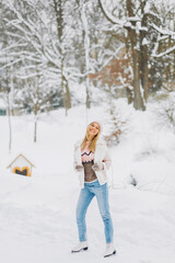 Happy beautiful girl wearing warm winter clothes ice skating in the park