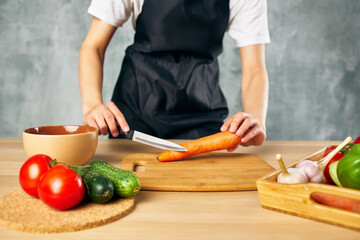 Woman in black apron on the kitchen cutting vegetables