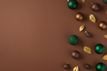 Top view photo of christmas tree decorations green brown golden balls and golden leaves on isolated brown background with empty space