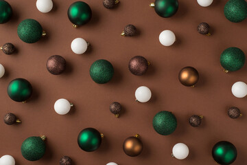 Top view photo of green white brown and golden christmas tree balls on isolated brown background