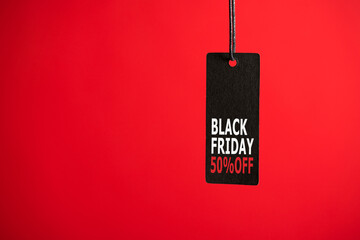 Photo of hanging black price tag on isolated red background with text 50% off