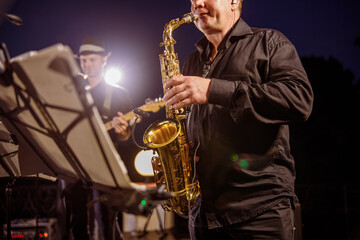 Naklejka premium Saxophone player playing in orchestra at night outdoor concert