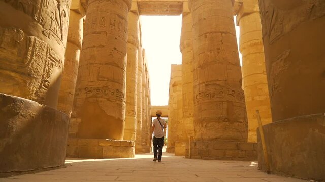 A young woman walking through the Karnak temple and its beautiful hieroglyphic columns, the great sanctuary of Amun. Egypt
