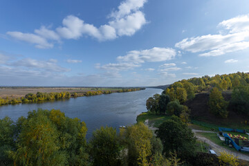Fototapeta na wymiar Autumn landscape with a view of the river and endless expanses of fields. Panoramic landscape with river and field and trees.