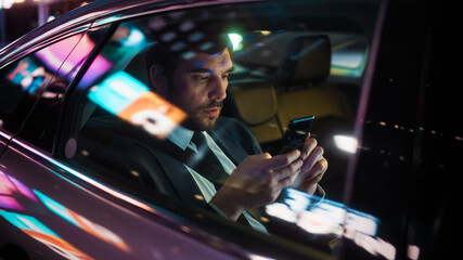 Handsome Businessman in a Suit Commuting from Office in a Backseat of His Luxury Car at Night....