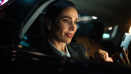Beautiful Businesswoman is Commuting from Office in a Backseat of Her Car at Night. Entrepreneur...