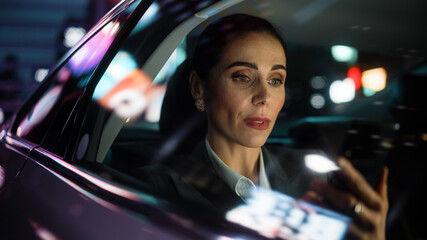 Beautiful Businesswoman is Commuting from Office in a Backseat of Her Car at Night. Entrepreneur...