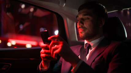 Successful Businessman in a Suit Commuting from Office in a Backseat of His Car at Night....