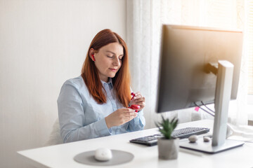 Attractive young assistance businesswoman listening music through wireless headphones is working on PC in office