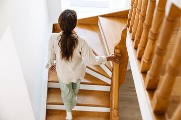 Obraz na płótnie Canvas Young black woman wearing pajama walking upstairs