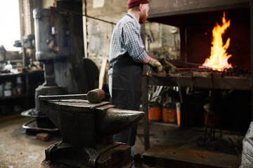 Image of work tool for forging the iron with blacksmith working in the background