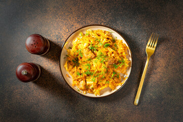 Braised cabbage. Stewed cabbage or bigos with turkey meat in a ceramic plate on a dark background. Traditional Polish dish