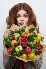 portrait of a woman fun posing fruit bouquet vitamins light background