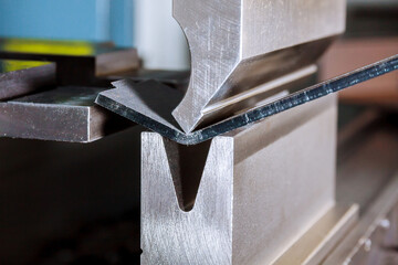 Work on a CNC bending machine in a factory. Sheet metal bending on a high-precision sheet metal...