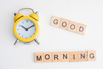 Yellow alarm clock with bell and Good morning text from wooden cubes