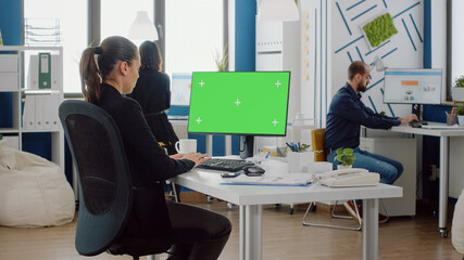 Corporate employee using computer with horizontal green screen for business project. Businesswoman...